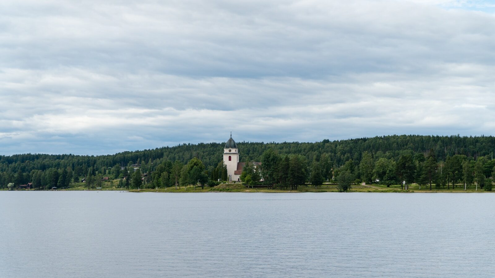 a body of water with trees and a building in the background